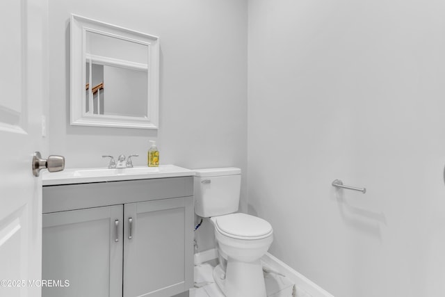 bathroom featuring vanity, toilet, baseboards, and marble look tile flooring