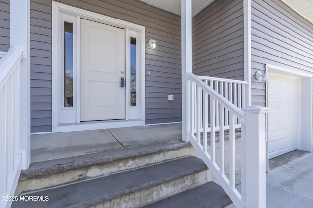view of exterior entry with a garage and a porch
