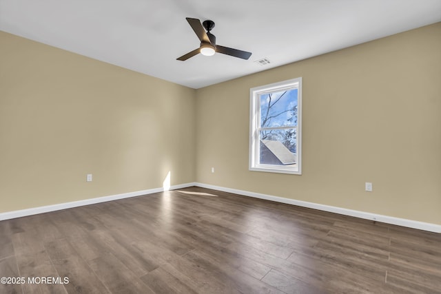 empty room with dark wood-style flooring, ceiling fan, and baseboards