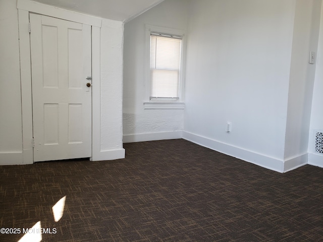 empty room with baseboards and dark colored carpet