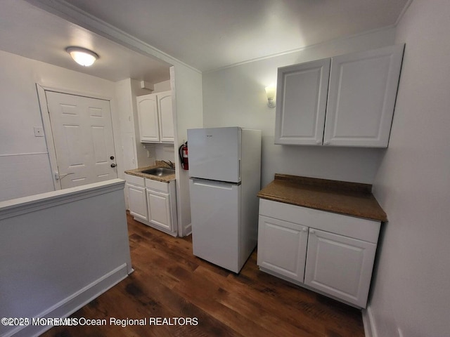 kitchen with freestanding refrigerator, dark wood-style flooring, white cabinetry, and a sink