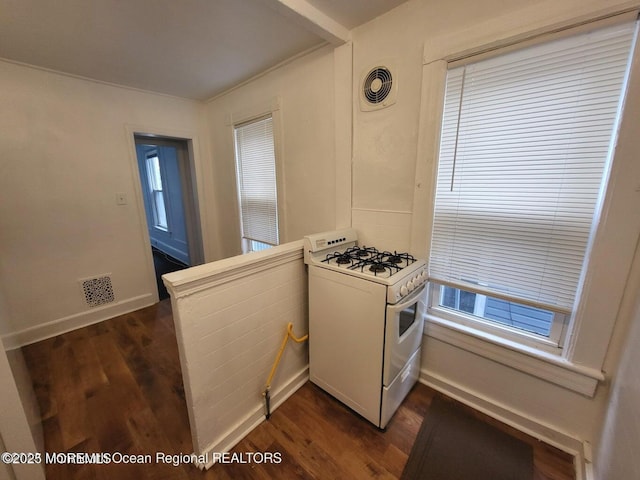 kitchen with gas range gas stove, dark wood finished floors, baseboards, and a peninsula