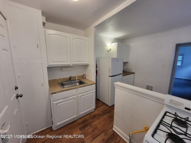 kitchen featuring white appliances, a sink, dark wood finished floors, white cabinetry, and light countertops
