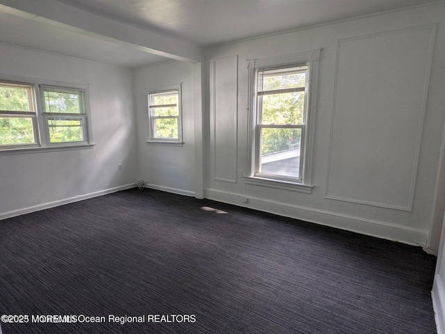 empty room with dark colored carpet and baseboards