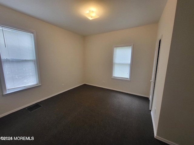 unfurnished room featuring baseboards and dark carpet