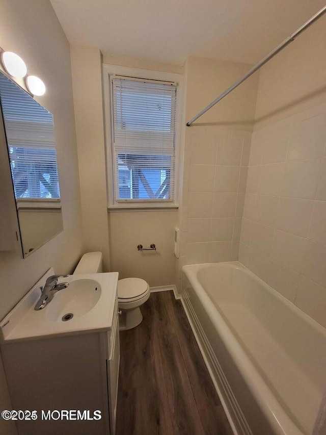 full bath featuring wood finished floors, toilet, vanity, and washtub / shower combination