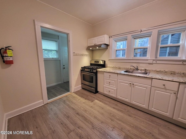kitchen with gas stove, a sink, under cabinet range hood, white cabinets, and light wood-type flooring