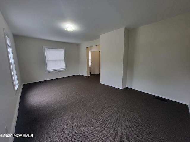 unfurnished room with dark carpet and baseboards