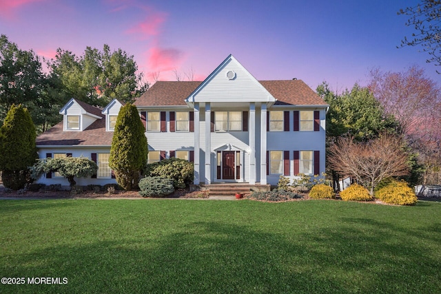greek revival inspired property featuring a lawn and a shingled roof