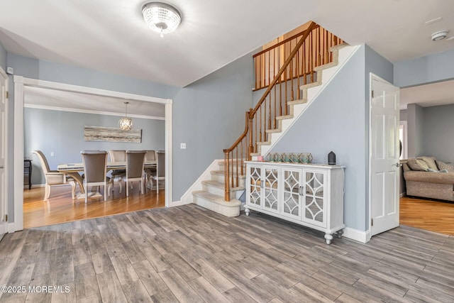 entryway featuring stairs, wood finished floors, baseboards, and ornamental molding