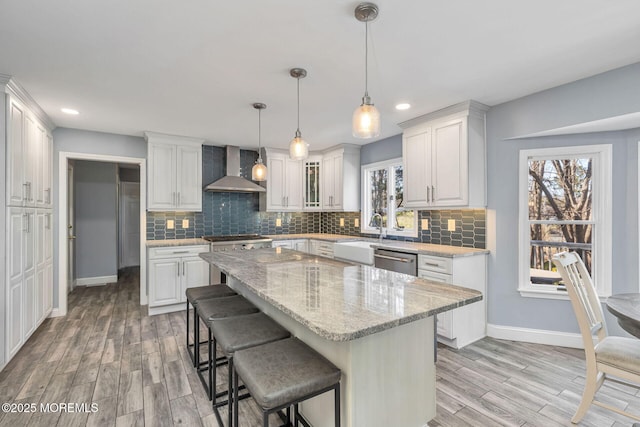 kitchen featuring wall chimney exhaust hood, appliances with stainless steel finishes, baseboards, light wood finished floors, and recessed lighting