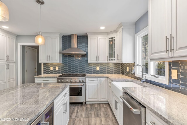 kitchen featuring wall chimney exhaust hood, stainless steel appliances, white cabinets, and recessed lighting