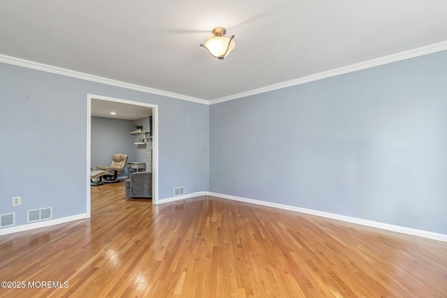 spare room with baseboards, ornamental molding, and light wood finished floors