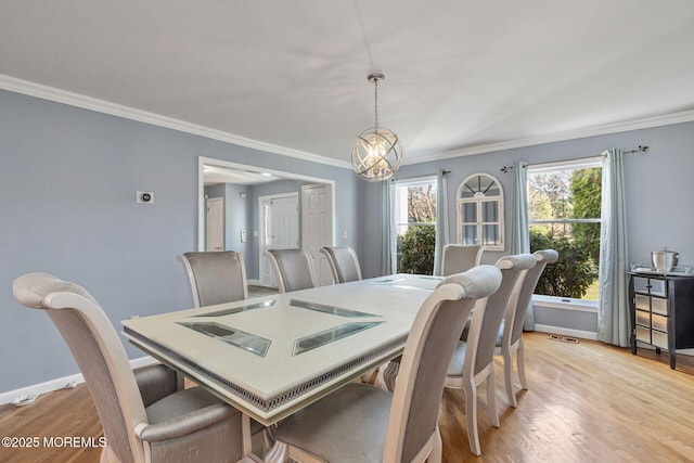 dining area with light wood-style floors, ornamental molding, a chandelier, and baseboards