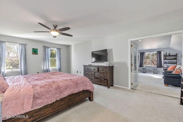 bedroom featuring multiple windows, light carpet, a ceiling fan, and baseboards