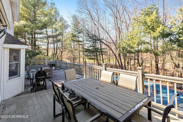 wooden deck with outdoor dining area and view of scattered trees