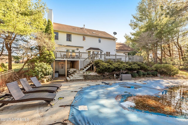 rear view of property with stairs, a wooden deck, a covered pool, a patio, and fence