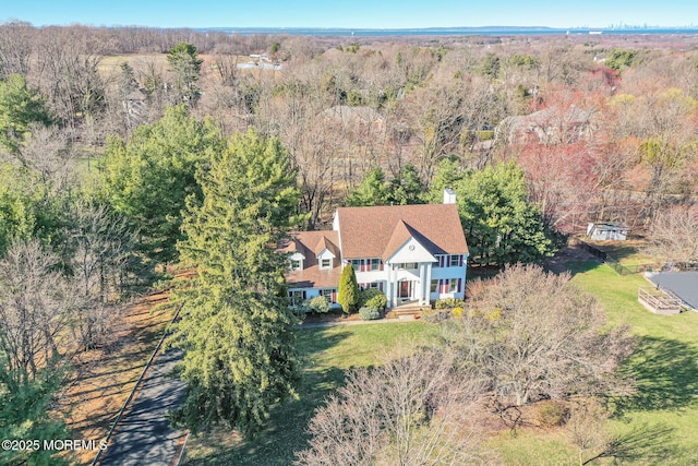 aerial view of property and surrounding area featuring a heavily wooded area