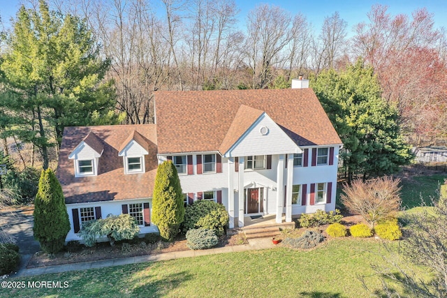 view of front facade with a front lawn and a shingled roof