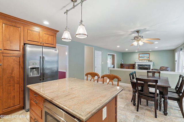 24 Statesboro Rd, Freehold, NJ 07728 - kitchen featuring stainless steel fridge, brown cabinetry, ceiling fan, a kitchen island, and a fireplace