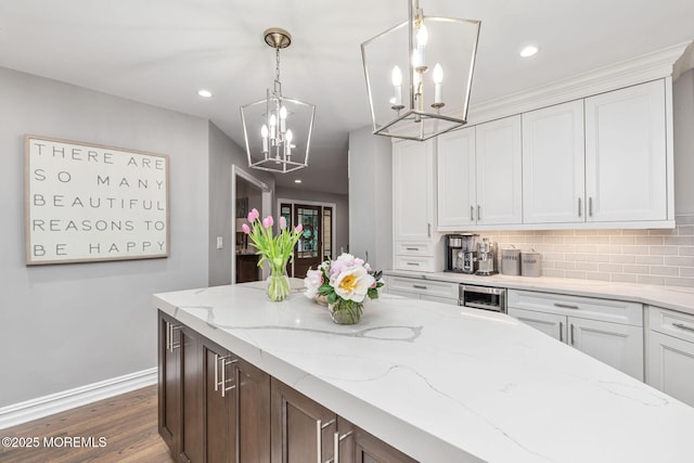 kitchen featuring a chandelier, baseboards, decorative backsplash, white cabinets, and recessed lighting