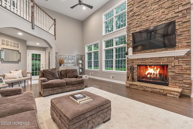 3 Ardmore Pl, Holmdel, NJ 07733 - living room with a ceiling fan, a stone fireplace, wood finished floors, a towering ceiling, and arched walkways