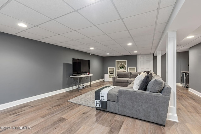 living area featuring baseboards, wood finished floors, a drop ceiling, and recessed lighting