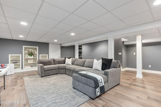 living area featuring light wood-type flooring, baseboards, a drop ceiling, and recessed lighting