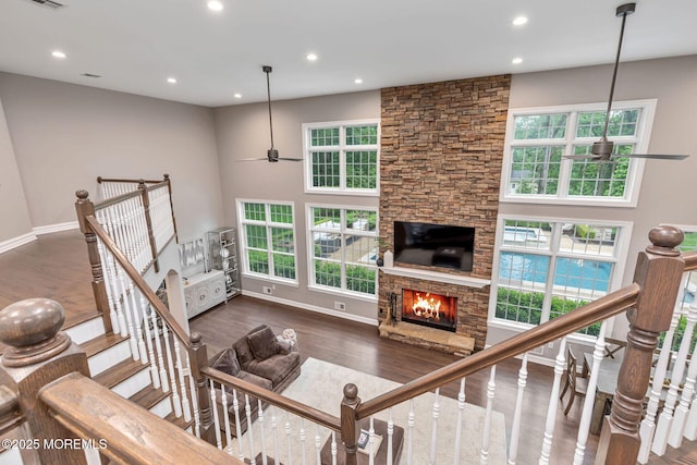 living area featuring ceiling fan, recessed lighting, healthy amount of natural light, a stone fireplace, and wood finished floors