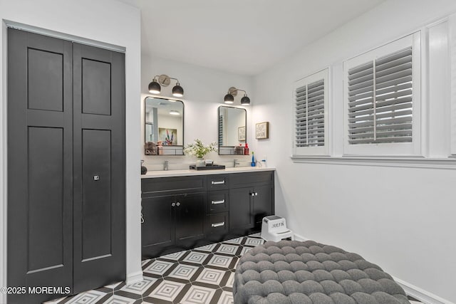 bathroom with double vanity, baseboards, and tile patterned floors