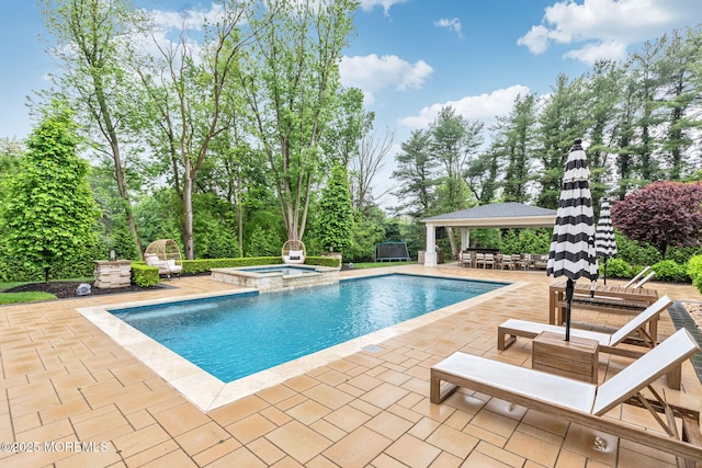 view of pool featuring a gazebo, a patio area, a pool with connected hot tub, and view of scattered trees