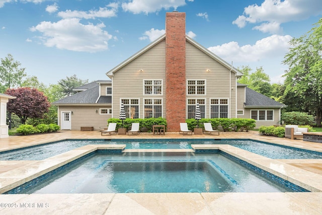 outdoor pool featuring an in-ground hot tub and a patio area