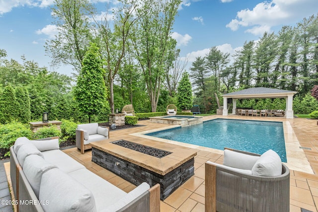 view of swimming pool with a gazebo, a patio area, an outdoor living space with a fire pit, view of wooded area, and a pool with connected hot tub