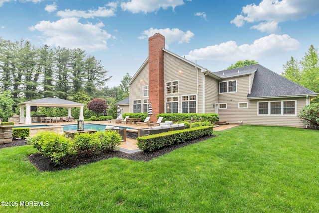 back of house with a gazebo, a chimney, a yard, an outdoor pool, and a shingled roof