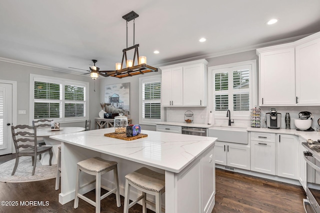kitchen with a sink, ornamental molding, tasteful backsplash, white cabinets, and a center island