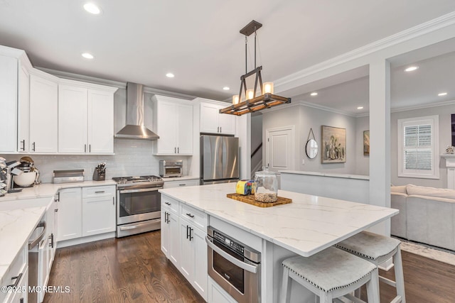kitchen featuring appliances with stainless steel finishes, wall chimney range hood, ornamental molding, dark wood finished floors, and recessed lighting