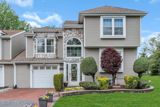 view of front of home featuring stone siding, decorative driveway, a garage, a front yard, and roof with shingles