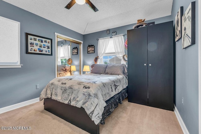 carpeted bedroom featuring a textured ceiling, a closet, ceiling fan, and baseboards