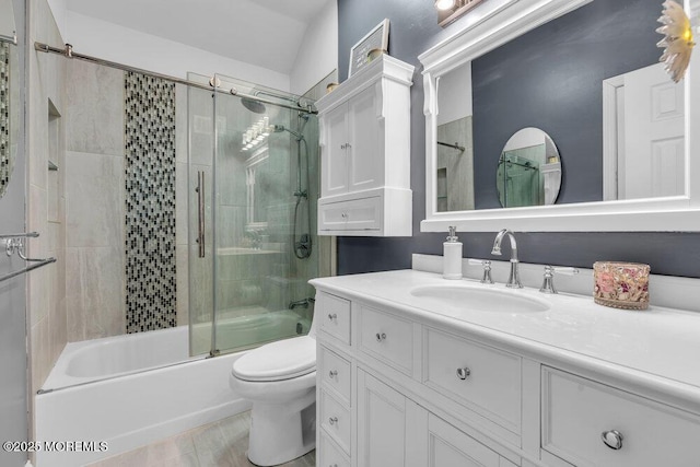 bathroom featuring toilet, combined bath / shower with glass door, vanity, and wood finished floors