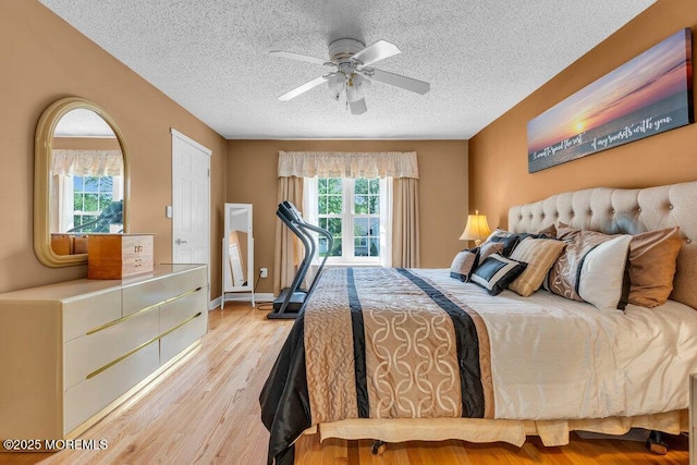 bedroom with multiple windows, a textured ceiling, light wood-style floors, and a ceiling fan