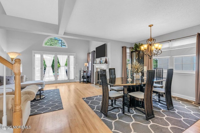 dining space with a chandelier, wood finished floors, beamed ceiling, and baseboards