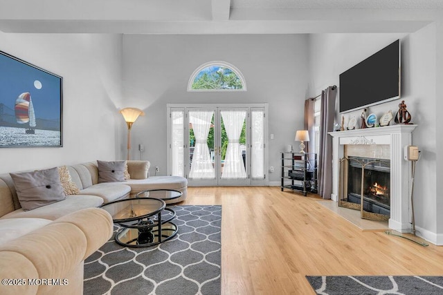 living area featuring wood finished floors, a high end fireplace, a towering ceiling, and beamed ceiling