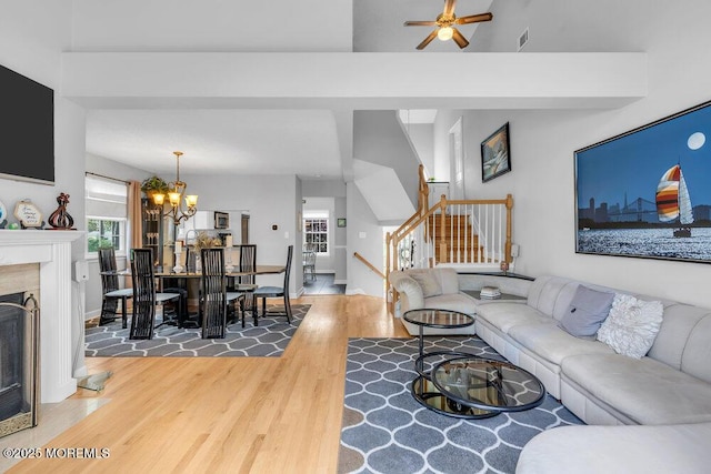 living area with wood finished floors, stairs, ceiling fan, baseboards, and a chandelier
