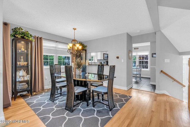 dining area with a chandelier, wood finished floors, a textured ceiling, and baseboards