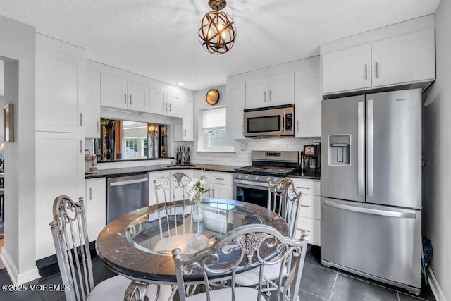 kitchen featuring appliances with stainless steel finishes, dark countertops, white cabinets, and a textured ceiling