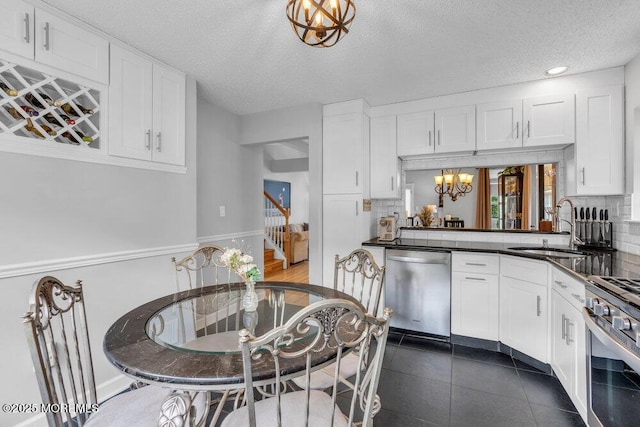 kitchen with a sink, stainless steel appliances, a chandelier, white cabinets, and dark countertops