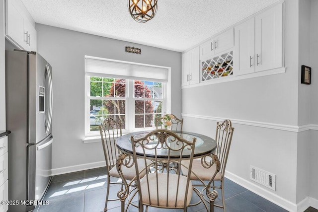 dining area with dark tile patterned floors, a textured ceiling, and baseboards