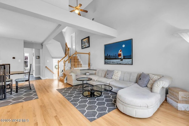 living area with wood finished floors, ceiling fan, stairway, and high vaulted ceiling