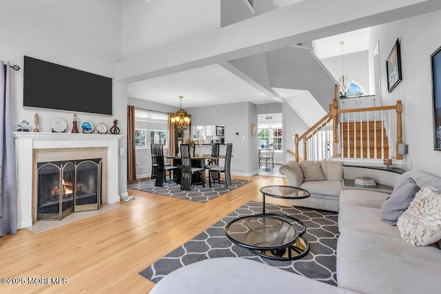 living area featuring a chandelier, wood finished floors, healthy amount of natural light, and a high ceiling