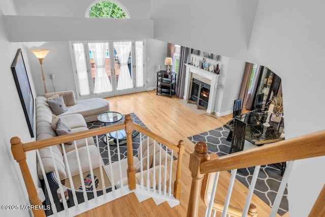 living room with a fireplace with flush hearth, wood finished floors, and a towering ceiling
